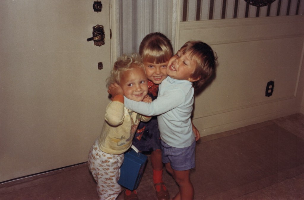 Three Westlake children in a group hug at home