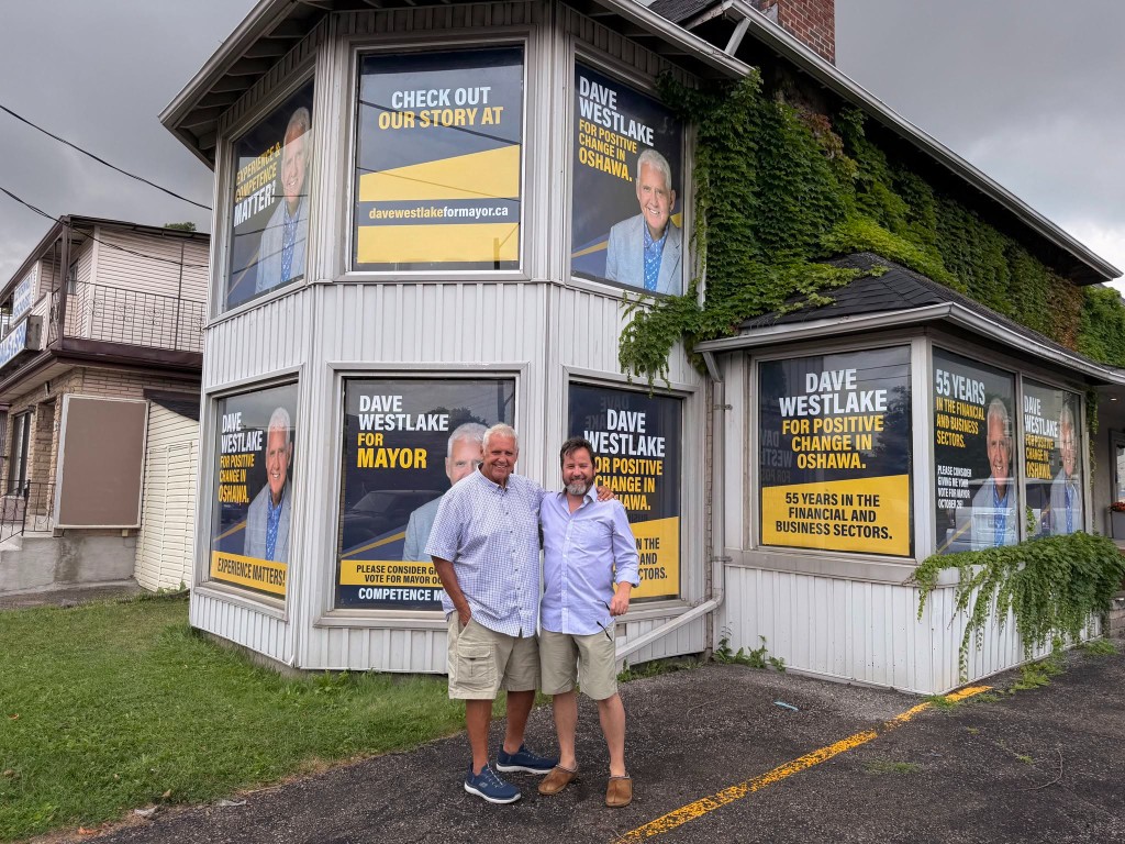 Dave Westlake and Jeff Davis in front of the campaign office window signs
