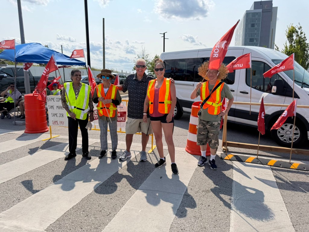 Dave Westlake standing with Unifor strikers holding union flags at Casino Ajax